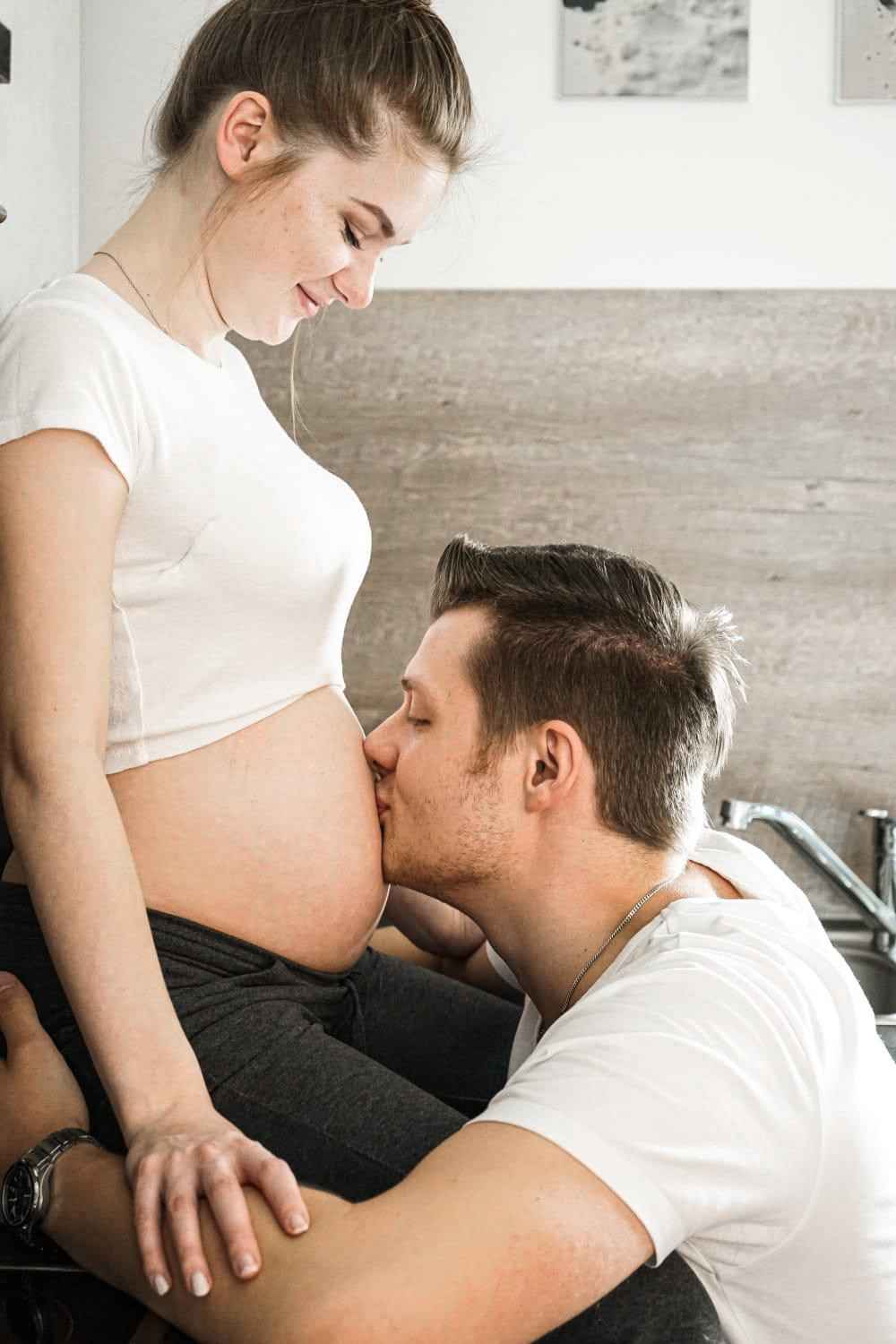 Mann küsst den Bauch seiner schwangeren Frau
